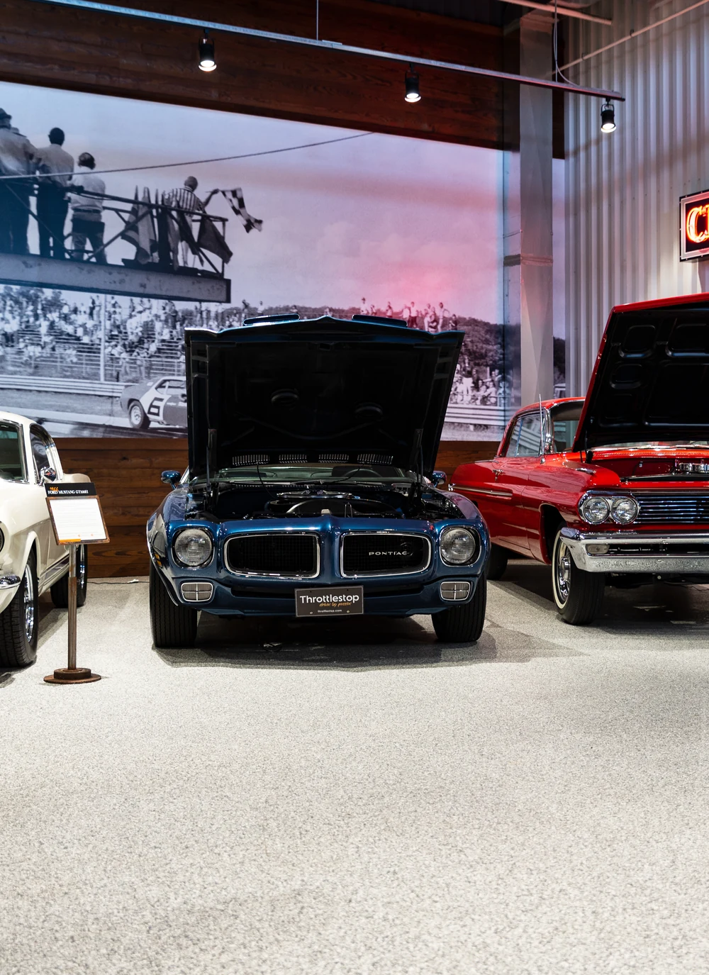 Classic cars parked on a light flake floor in a showroom garage.