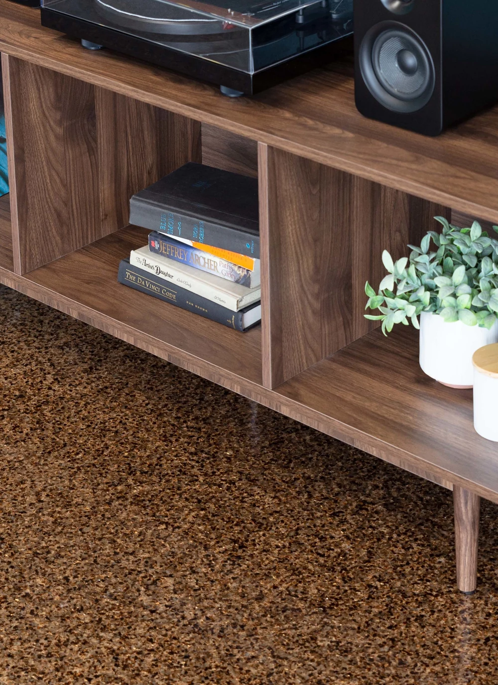 A warm copper coated concrete floor in a finished living space with a record player and shelving.