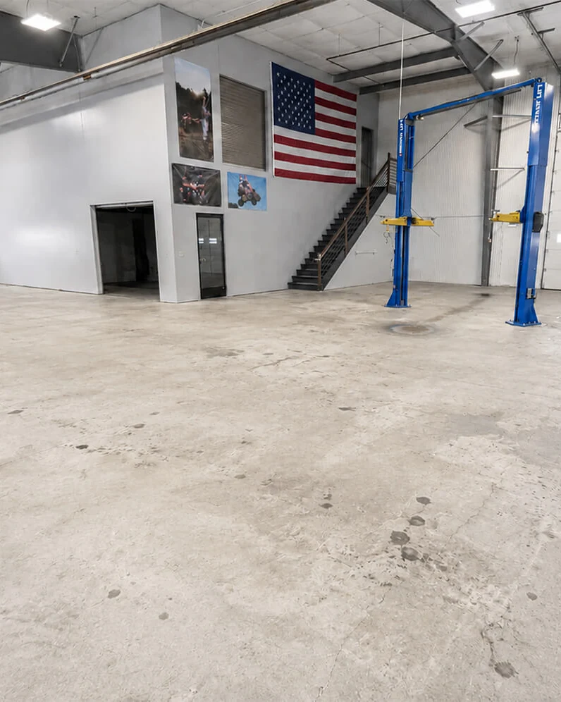 Reference photograph of bare concrete in a service shop with vehicle lifts.